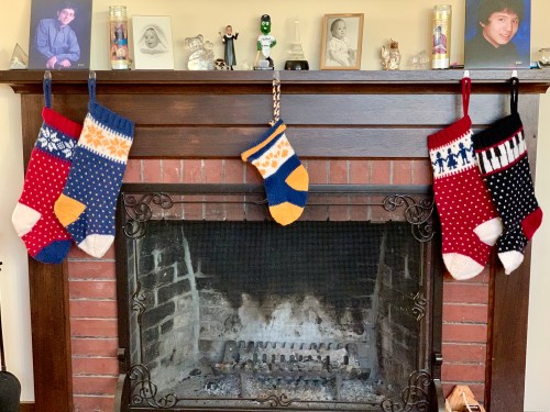 five handknit christmas stockings hanging from the fireplace mantel