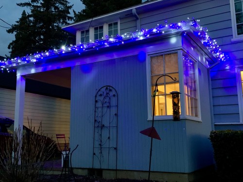 blue and white icicle lights decorating front porch gutters