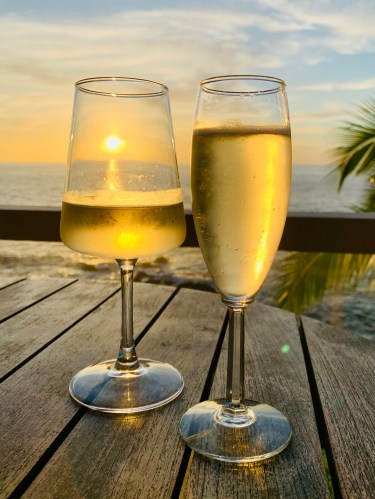 two wine glasses and a hawaiian sunset overlooking the pacific ocean