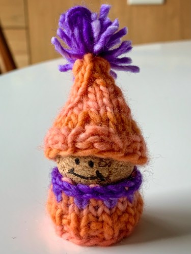 small cork korknisse wearing an orange and purple sweater and hat knit from malabrigo worsted