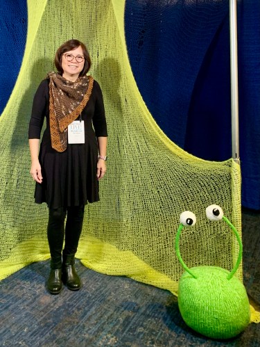 it shawlette standing in a knit art installation by Sarah Divi