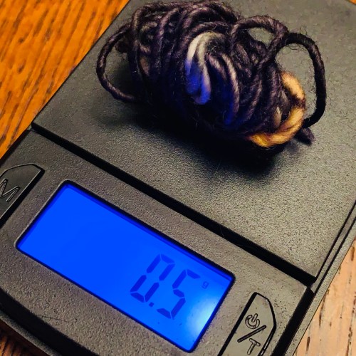 tiny ball of yarn on scale, weighing 0.5 grams