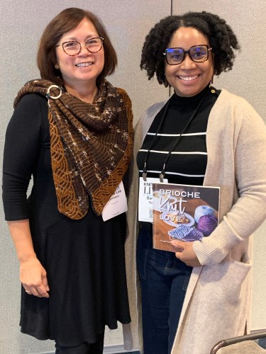 Two smiling women, one holding a copy of Brioche Knit Love book