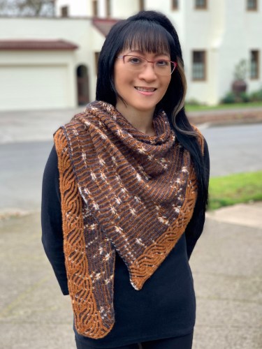 woman wearing a gray and caramel colored shawlette with white assigned pooling stars