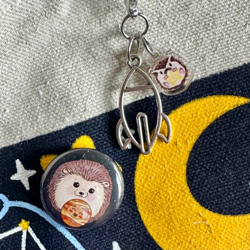 Zipper pull featuring a rocket and Melvin the hedgehog