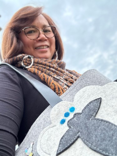 Me wearing a brioche and pooling shawlette, and holding a felted tote that features a sheep motif