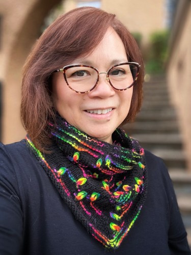 Woman wearing a hand knit cowl featuring assigned pooling flame motifs