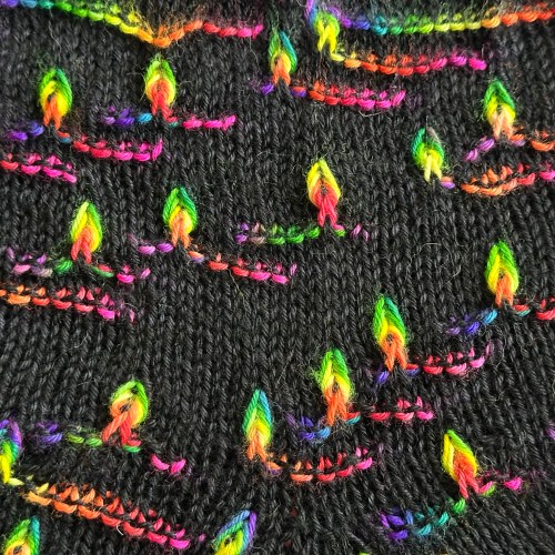 Detail of stockinette stitch with colorful assigned pooling flame motifs