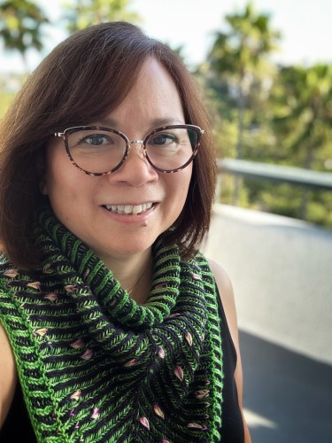 Woman wearing brioche knit cowl featuring assigned pooling petal motifs