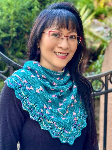 Woman wearing a teal colored hand knit cowl with assigned pooling fan motifs
