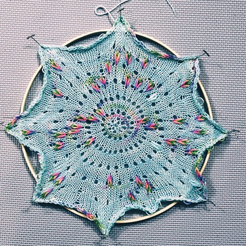 A knit circle being stretched over an embroidery hoop
