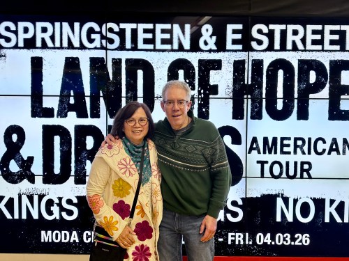 two people in front of a sign that reads Land of Hope and Dreams American Tour