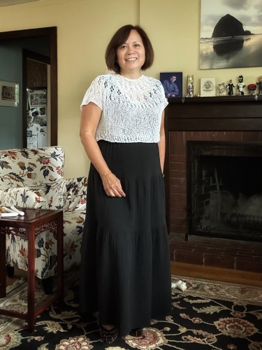 woman wearing a white pullover sweater over a black tiered dress